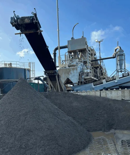 Aggregates falling off a conveyor belt with blue skies